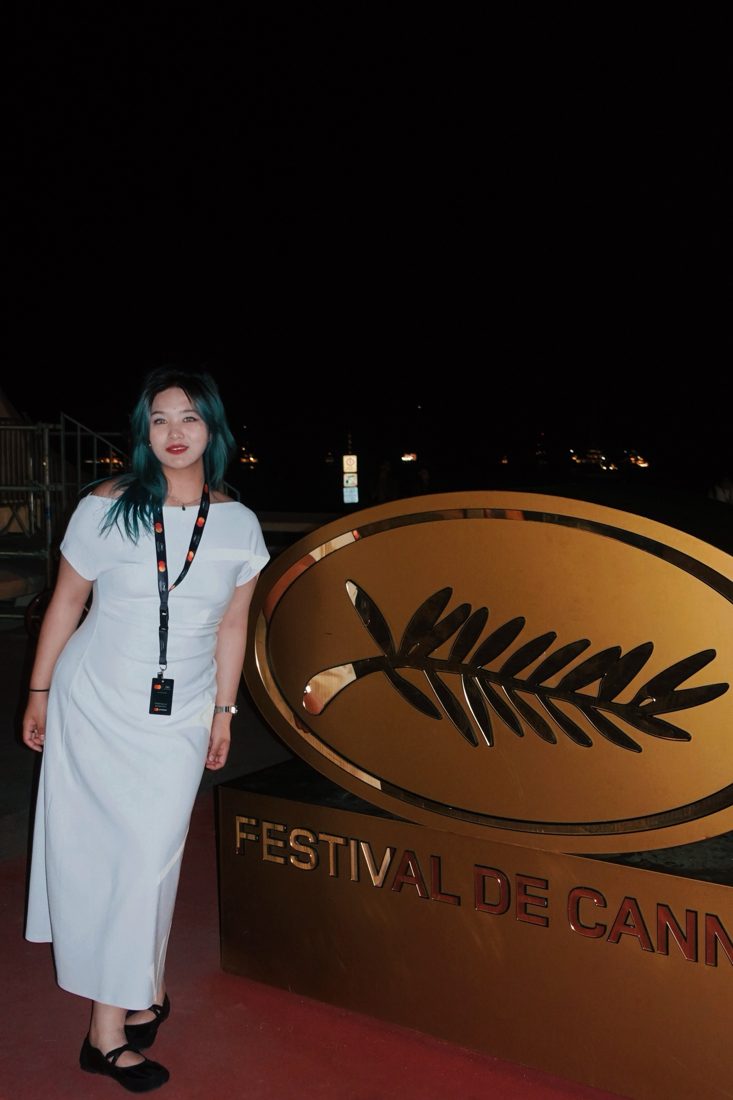 Ekon beside the Festival de Cannes palm sign at night